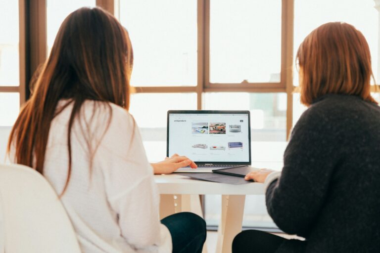 Die besten Social Media Agenturen aus Dortmund im Vergleich two women talking while looking at laptop computer